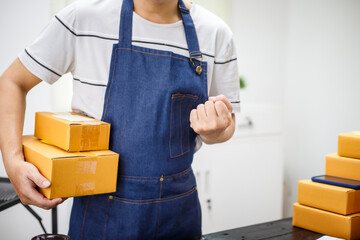 close-up of a man's hands working meticulously with a cardboard box on wooden desk, representing an...