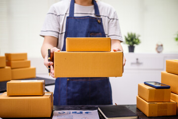 close-up of a man's hands working meticulously with a cardboard box on wooden desk, representing an...