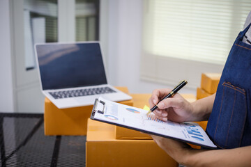 close-up of a man's hands working meticulously with a cardboard box on wooden desk, representing an...