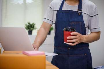 close-up of a man's hands working meticulously with a cardboard box on wooden desk, representing an...