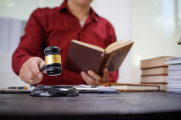 close-up of a lawyer’s hands working at a desk, reviewing legal documents and contracts, with a wooden gavel nearby, symbolizing law, legislation, and the potential complexities of bribery cases.