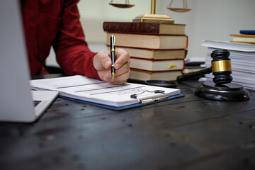 close-up of a lawyer’s hands working at a desk, reviewing legal documents and contracts, with a...
