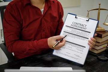 close-up of a lawyer’s hands working at a desk, reviewing legal documents and contracts, with a...