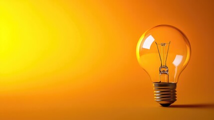 Glowing light bulb against yellow-orange gradient background