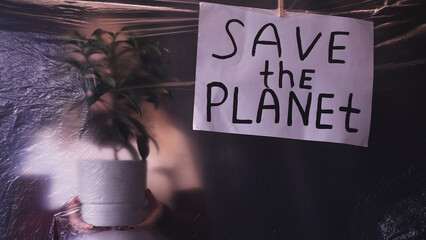 Save planet. Global warming. Climate change. Defocused silhouette with green plant behind creased...