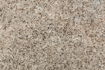 Close-up of a natural granite stone texture featuring beige and brown speckles, ideal for use in backgrounds, countertops, or design elements.