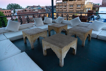 Decorated interior view of a roof top restaurant with wooden tables and cushions for relax of customers. Jodhpur, Rajasthan, India.