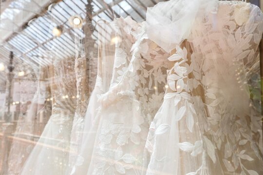 Close-up of lace, sheer fabric and silk chiffon wedding dresses on display at an upscale luxury bridal boutique inside The Strand Arcade — George St, Sydney; NSW, Australia - Powered by Adobe