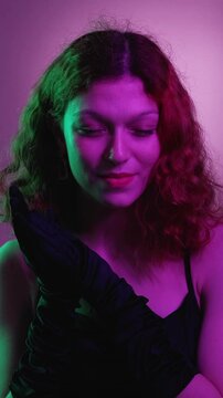 Vertical video. Evil woman. Cunning smile. Pretty glamour female scheming rub hands black gloves evening dress think revenge sneaky plan neon green violet gradient.