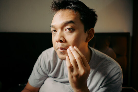 A man examining his facial hair while touching his chin, appearing thoughtful and focused