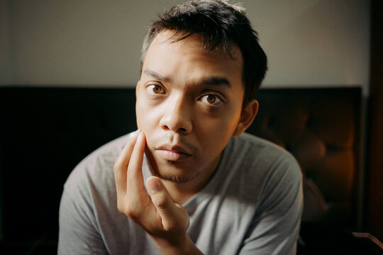 A man examining his facial hair while touching his chin, appearing thoughtful and focused
