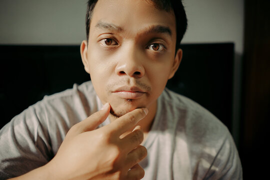 A man examining his facial hair while touching his chin, appearing thoughtful and focused