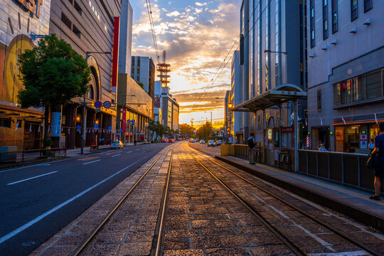 夕暮れの空と伊予鉄道の線路と都市風景