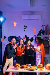 Halloween party with friends in costumes, enjoying drinks, food, and festive decorations. Perfect for autumn gatherings