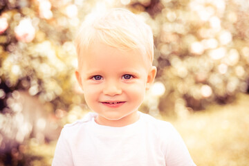 Adorable little girl boy closeup outdoors in summer. Kids face close up. Funny blonde little child close up portrait.