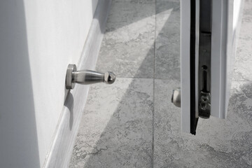 A close-up on a stainless steel wall mounted doorstop in a renovated apartment to prevent a door...