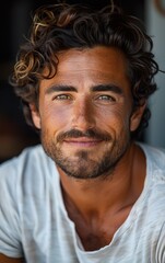 Obraz premium A man with a beard and a mustache is smiling at the camera. He is wearing a white shirt and has a green eye