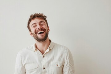 Obraz premium Happy young man laughing against a neutral background.