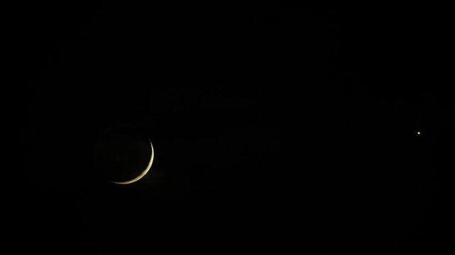 Thin crescent moon in dark night sky