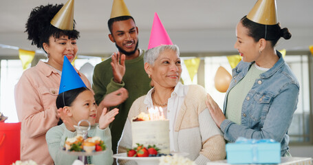 Family, happy and celebration with grandma on birthday for present, surprise and special event at home. Party hat, child and people with applause by senior woman for dessert, cake or candles by table