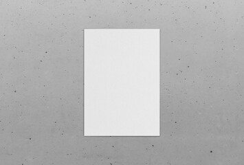 Poster mockup on concrete wall background. Empty white vertical rectangle poster mockup with soft shadow on neutral light grey background. Flat lay, top view