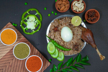 mutton biryani, leg piece biryani, chicken biryani along with cucumber slice, onion, onion raita, capsicum, cashews, almond, green peas, egg, chili powder, coriander powder and spices on silver bowl