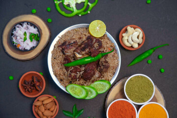 mutton biryani, beef biryani, chicken biryani along with cucumber slice, onion, onion raita, capsicum, cashews, almond, green peas, egg, chili powder, coriander powder and spices on silver bowl