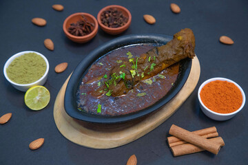 mutton leg gravy, mutton leg soup along with lemon slice, mint leaves, star anise, cinnamon, almond, chili powder, coriander powder and spices on black bowl in the wooden background
