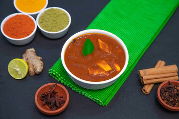 chicken fry, chicken gravy, mutton gravy along with lemon, ginger, garlic, chili powder, coriander powder, turmeric powder, cinnamon and spices on white plate and white bowl in the side of green towel