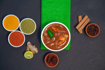 chicken fry, chicken gravy, mutton gravy along with lemon, ginger, garlic, chili powder, coriander powder, turmeric powder, cinnamon and spices on white plate and white bowl in the side of green towel