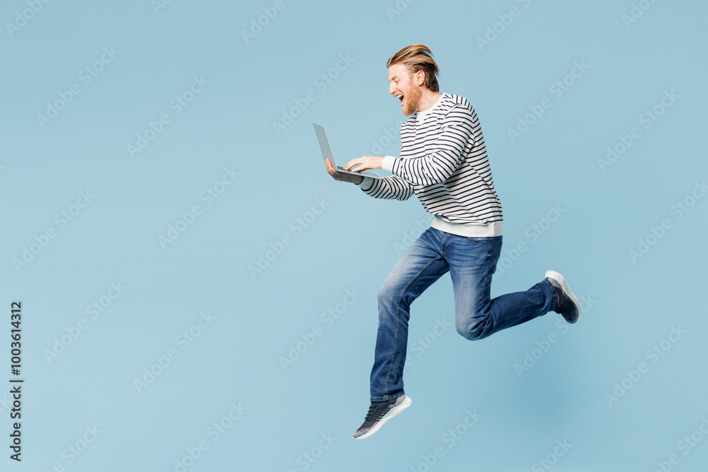 Wall mural Full body young happy IT man wear striped sweatshirt casual clothes jump high hold use work on laptop pc computer isolated on plain pastel light blue cyan background studio portrait Lifestyle concept