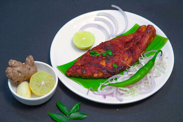 Fishy fry, Seer fish fry, salmon fish fry along with onion or onion slice, lemon, ginger, garlic, chili, cabbage, and spices on white bowl and white plate