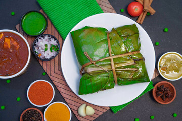 Vazhai ilai parotta, banana leaf parotta along with onion or creamy onion raita, lemon, Star anise, chicken gravy and spices on white plate