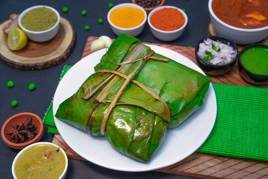 Vazhai ilai parotta, banana leaf parotta along with onion or creamy onion raita, lemon, tomato, Star anise, chicken gravy and spices on white plate