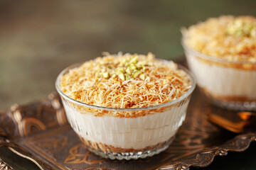 Traditional milky crispy Ramadan dessert custard pudding with roasted kadayif and diced pistachio . Kadayifli Muhallebi