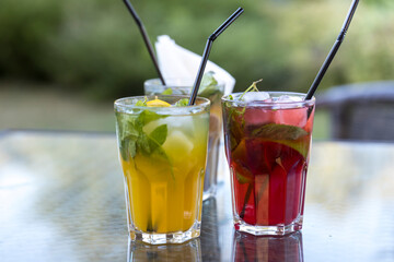 Three glasses of different colored drinks sit on a table