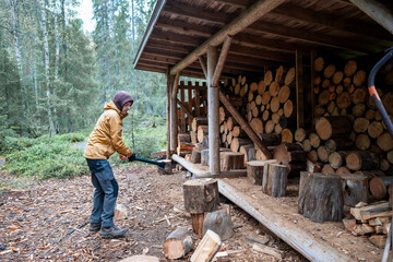 man chopping firewood with an axe for making a fire in the forest