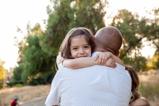 A young girl hugging her dad, smiling over their shoulder