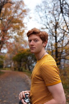 A young man wearing a striped shirt stands on a winding path