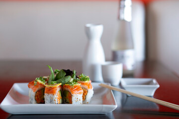 Colorful sushi roll on plate with chop sticks and sake © Cavan