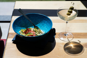 Vibrant blue bowl with lobster dish and martini on table
