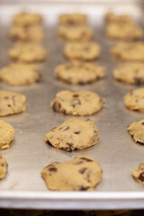 Close up on rows of chocolate chip cookie dough on sheet pan