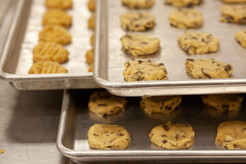 Sheet pans of raw chocolate chip and peanut butter cookie dough