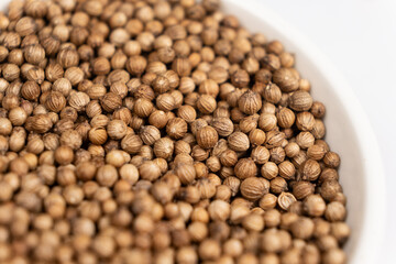 Coriander grains in a plate macro top view.