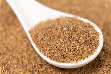 Ground coriander natural spice in a spoon close-up.
