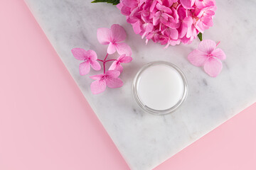 Cosmetic jar with natural colorless lip balm on a marble flower podium. pleasant aroma. Perfect for makeup. top view. copy space. Care, beauty concept