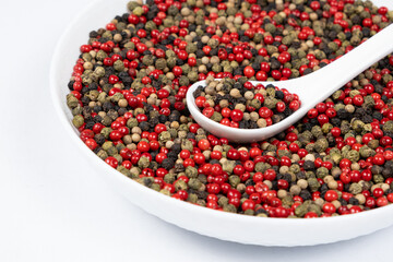Different varieties of peppercorns, red, green, black and white peppers in a spoon