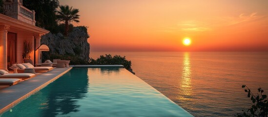 Fototapeta premium Sunset over the ocean from a luxury villa with an infinity pool.
