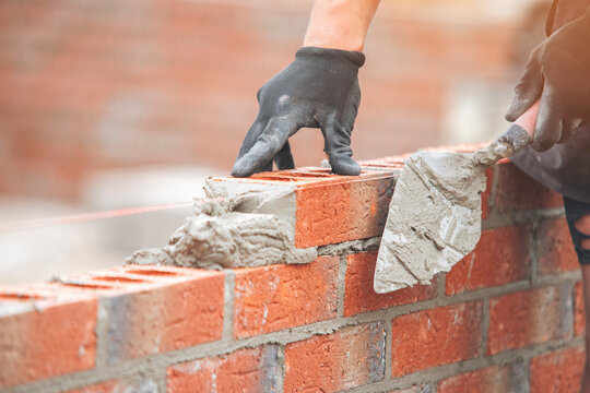 Skilled craftsman laying bricks for new wall in construction project during daylight hours