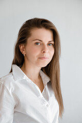 Young smiling confident business woman wearing white top shirt casual clothes looking camera isolated on grey background studio portrait. Vertical shot. Lifestyle concept. Professional office worker